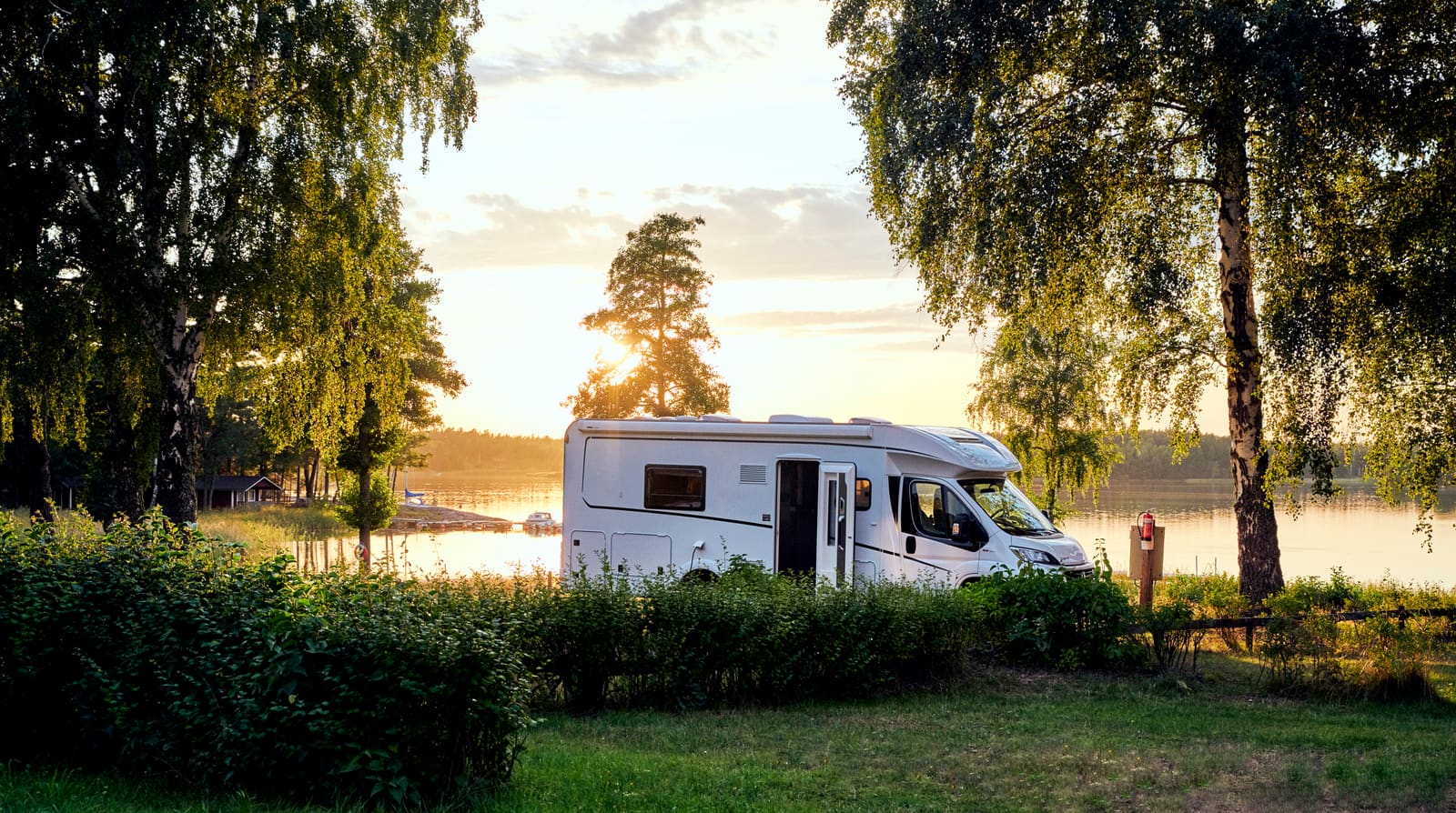 A motorhome parked by a lake at sunset