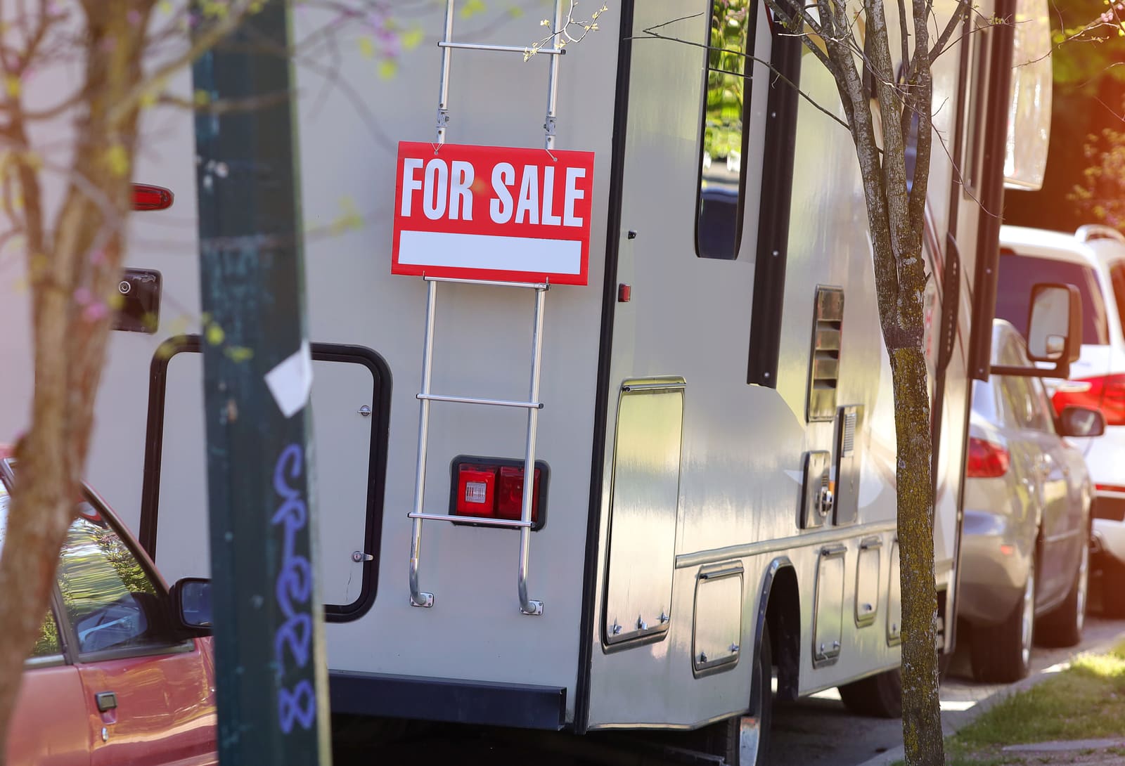 A motorhome with a For Sale sign parked on a street