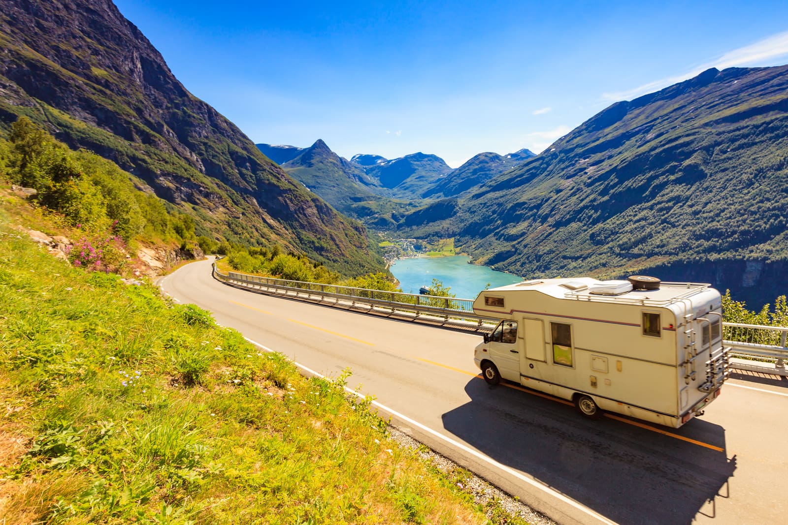 A motorhome driving along a mountain road above a fjord